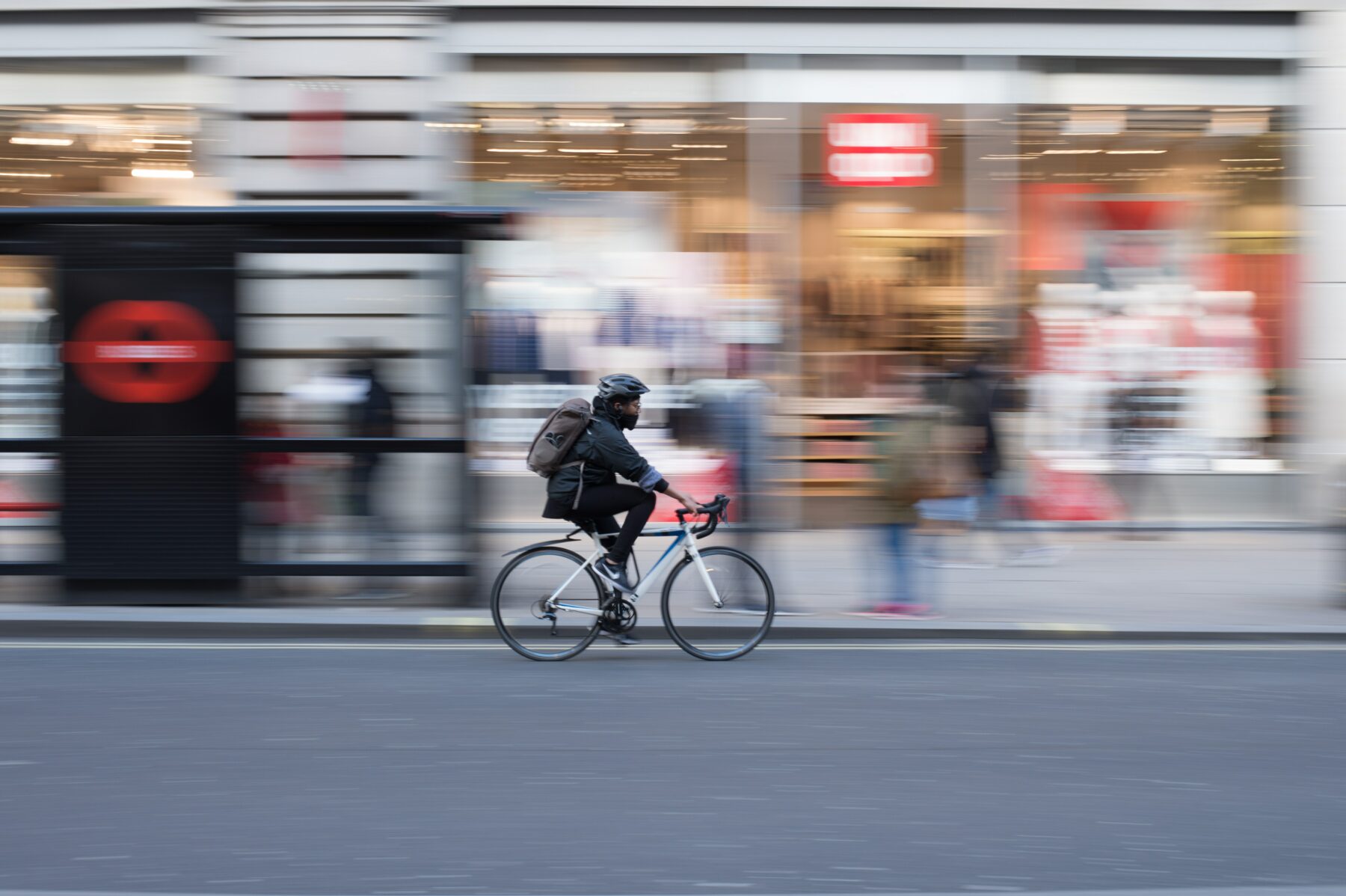 man cycling at high speed past shops in London